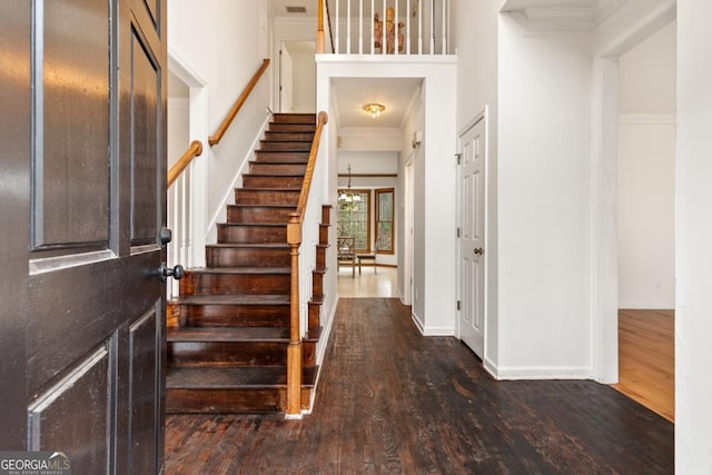 foyer entrance with dark wood-style flooring, crown molding, and stairs