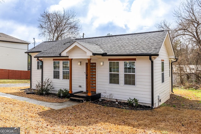 bungalow-style home featuring fence and roof with shingles