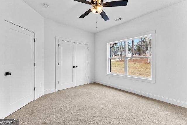 unfurnished bedroom featuring ceiling fan, a closet, and light carpet