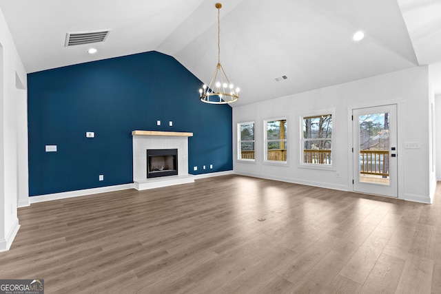 unfurnished living room featuring high vaulted ceiling, hardwood / wood-style floors, and an inviting chandelier