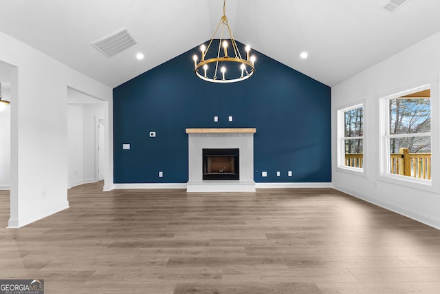 unfurnished living room with an inviting chandelier, wood-type flooring, and lofted ceiling