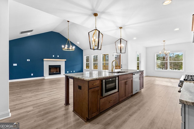 kitchen with stainless steel dishwasher, sink, a kitchen island with sink, and hanging light fixtures