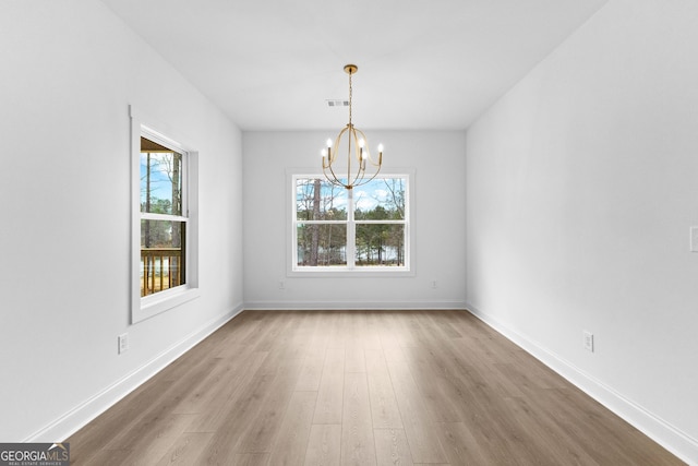 unfurnished dining area featuring a chandelier and hardwood / wood-style floors