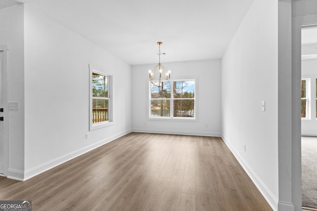 unfurnished dining area featuring hardwood / wood-style floors and an inviting chandelier