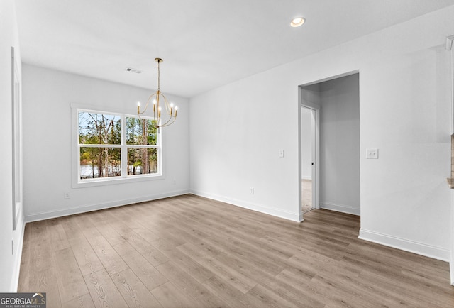 empty room with an inviting chandelier and hardwood / wood-style floors