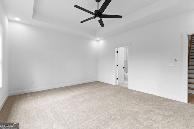 carpeted spare room featuring ceiling fan and a tray ceiling