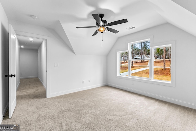 additional living space with ceiling fan, light colored carpet, and vaulted ceiling