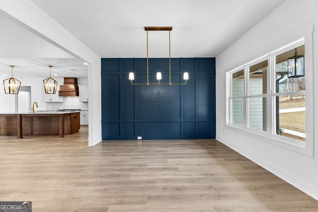 interior space with a healthy amount of sunlight, custom range hood, pendant lighting, and a notable chandelier