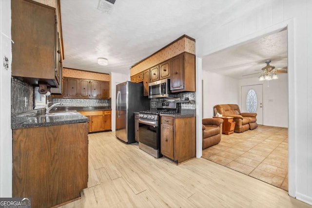 kitchen with tasteful backsplash, sink, light hardwood / wood-style floors, and appliances with stainless steel finishes