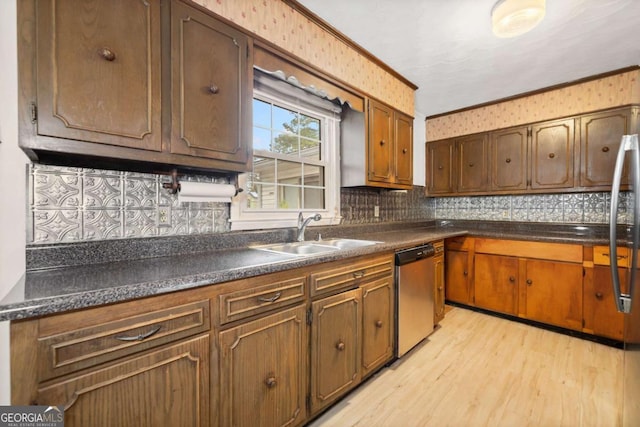 kitchen featuring sink, backsplash, ornamental molding, stainless steel dishwasher, and light wood-type flooring