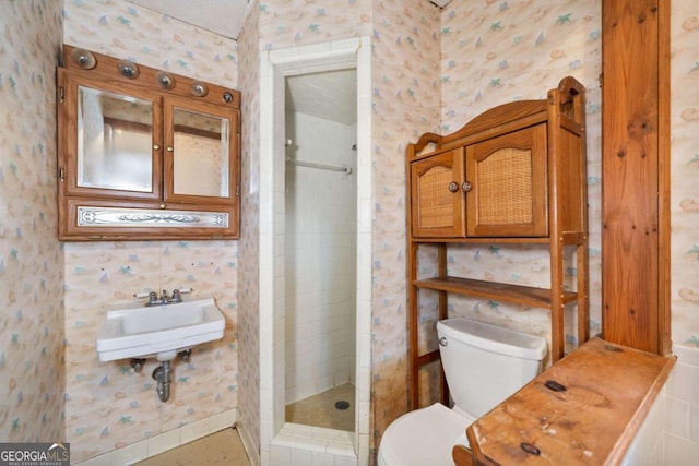 bathroom featuring toilet, sink, and a tile shower