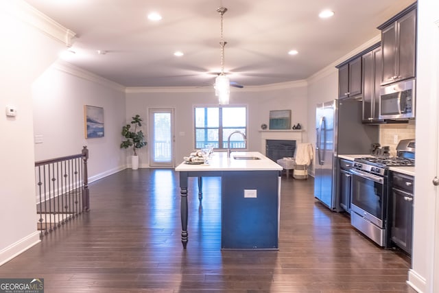 kitchen featuring crown molding, stainless steel appliances, sink, and an island with sink