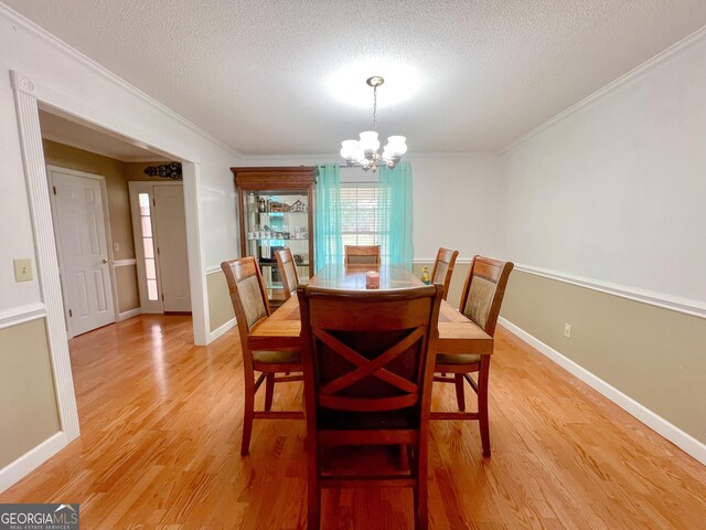 dining space featuring hardwood / wood-style flooring, ornamental molding, and a textured ceiling