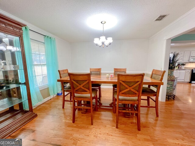 dining room featuring crown molding, a textured ceiling, a notable chandelier, and light hardwood / wood-style floors