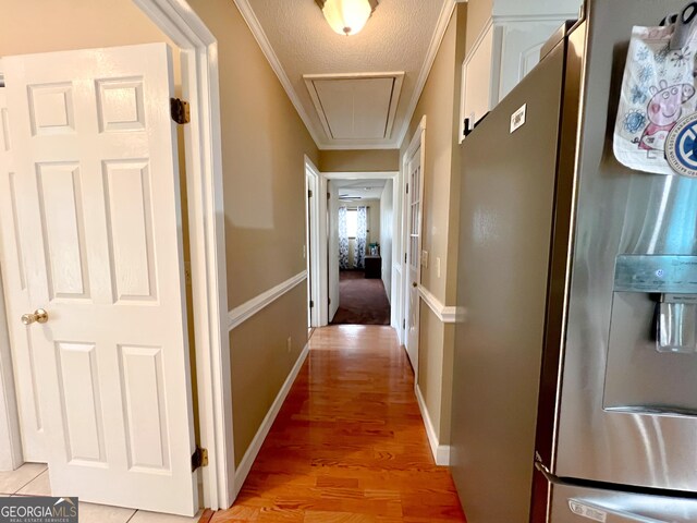 hall with ornamental molding, a textured ceiling, and light hardwood / wood-style flooring