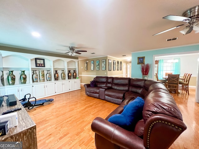 living room featuring ornamental molding, light hardwood / wood-style floors, and ceiling fan