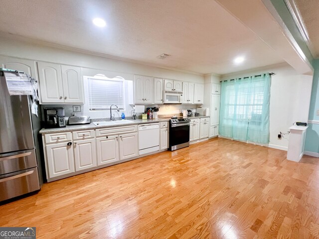 kitchen featuring white cabinetry, appliances with stainless steel finishes, sink, and light wood-type flooring