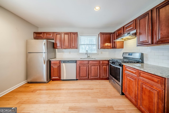 kitchen with sink, light hardwood / wood-style flooring, appliances with stainless steel finishes, backsplash, and light stone countertops