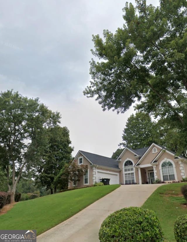 view of front facade with driveway, a garage, and a front yard