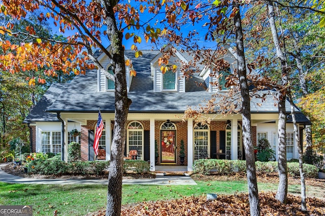 cape cod house featuring a front lawn and covered porch