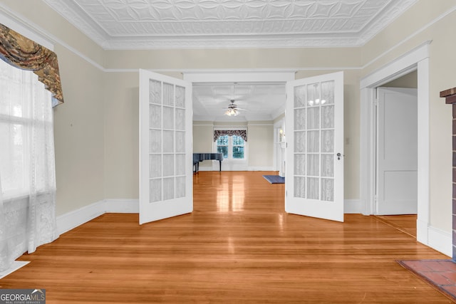 empty room featuring crown molding, french doors, ceiling fan, and hardwood / wood-style flooring