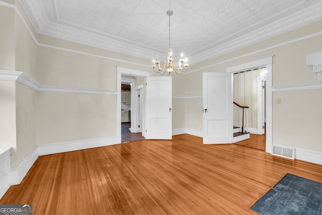 unfurnished dining area featuring a chandelier, wood finished floors, stairway, baseboards, and an ornate ceiling