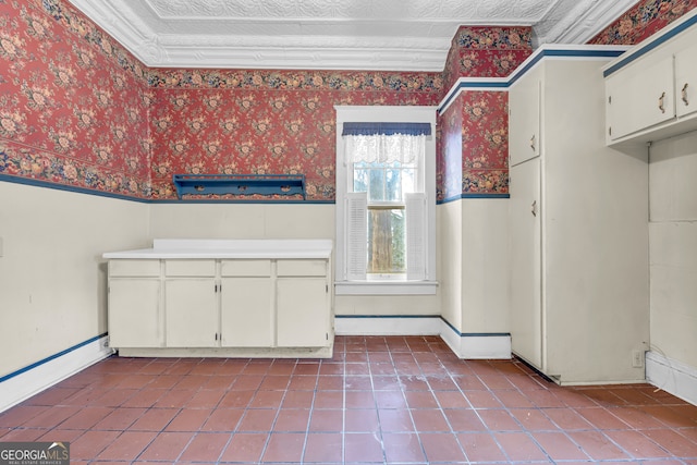 kitchen with wallpapered walls, white cabinets, tile patterned floors, baseboards, and light countertops
