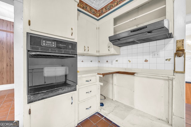 kitchen featuring wall chimney range hood, dark tile patterned floors, white cabinetry, decorative backsplash, and oven