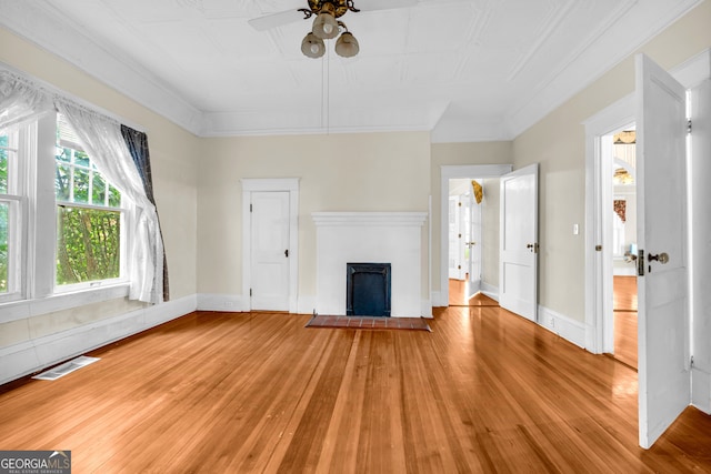 unfurnished living room with hardwood / wood-style floors, ornamental molding, and ceiling fan