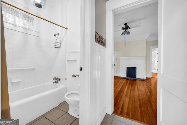 full bath with a fireplace with raised hearth, ceiling fan, tile patterned flooring, shower / bath combination, and crown molding