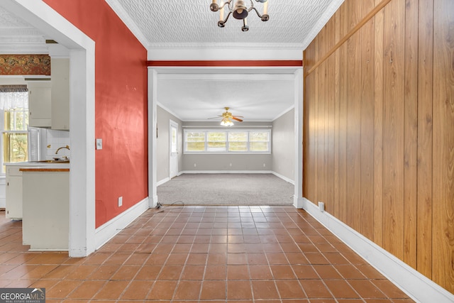 corridor featuring tile patterned floors, ornamental molding, and wood walls