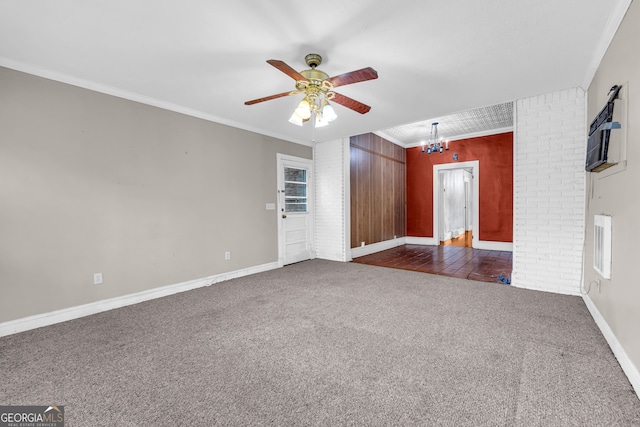 unfurnished living room featuring dark colored carpet, ornamental molding, and ceiling fan with notable chandelier