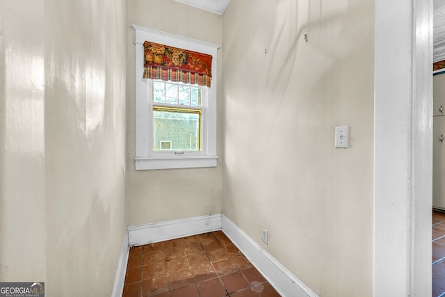 empty room with baseboards and dark tile patterned floors