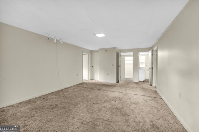 unfurnished bedroom featuring carpet flooring, rail lighting, and baseboards