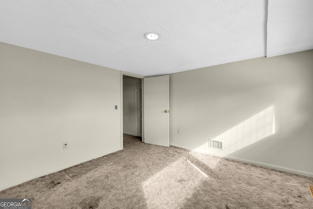 carpeted empty room featuring baseboards and a textured ceiling
