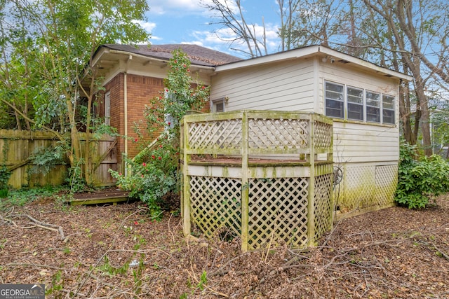 rear view of house featuring fence, a deck, and brick siding