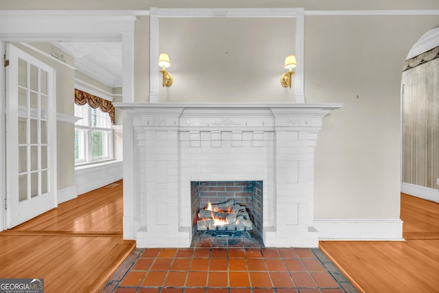 detailed view of a brick fireplace, ornamental molding, baseboards, and wood finished floors