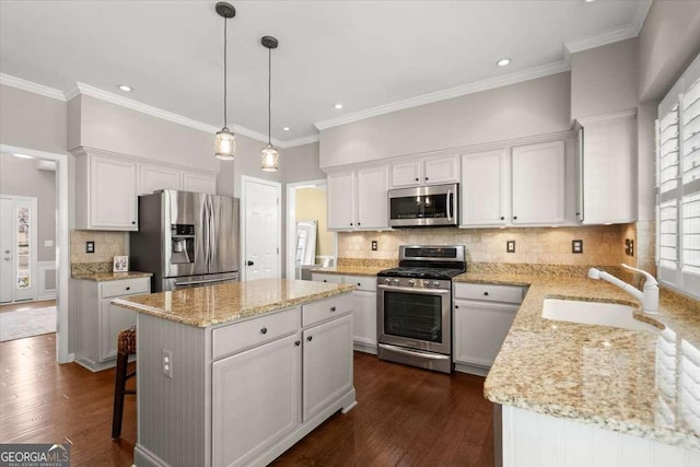 kitchen with a kitchen island, appliances with stainless steel finishes, pendant lighting, white cabinetry, and sink