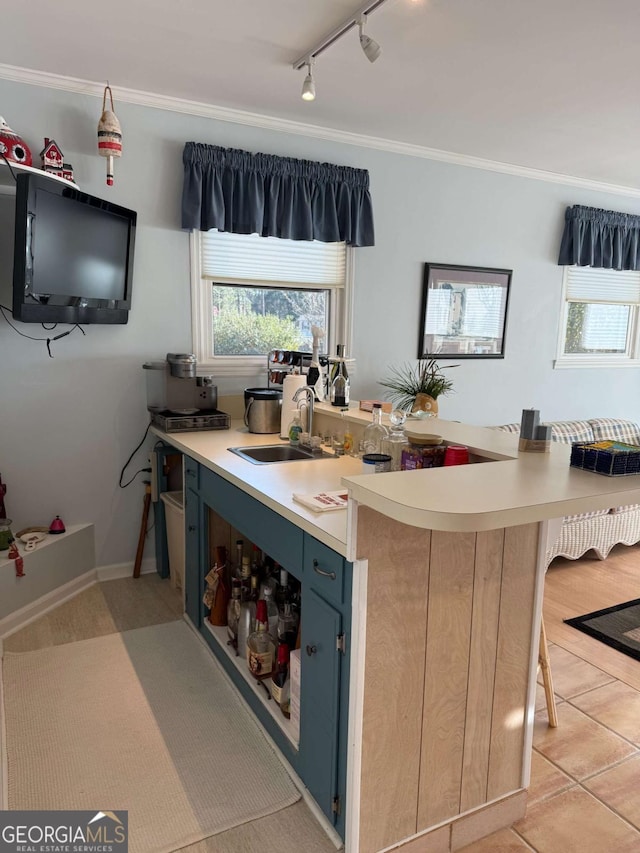 kitchen with light countertops, ornamental molding, a sink, and blue cabinets