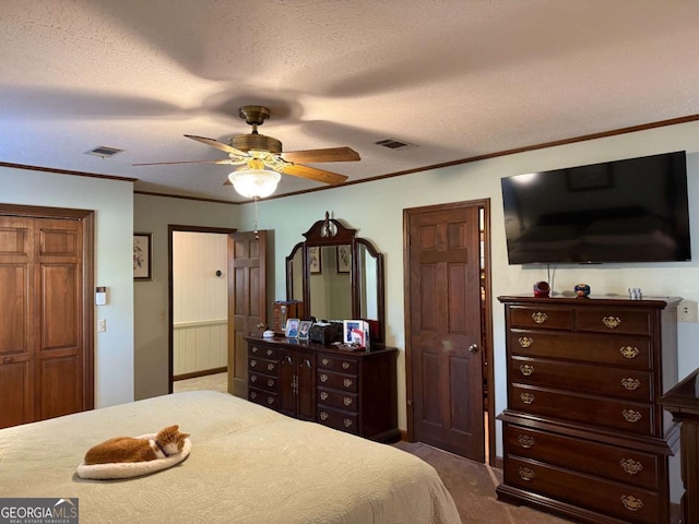 bedroom featuring visible vents, dark carpet, a textured ceiling, and ornamental molding