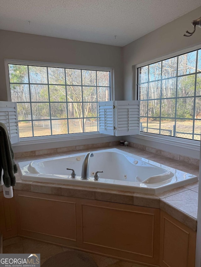 full bathroom featuring a tub with jets and a textured ceiling