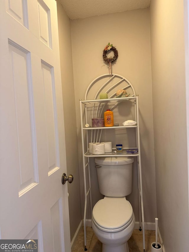 bathroom with baseboards, a textured ceiling, toilet, and tile patterned floors