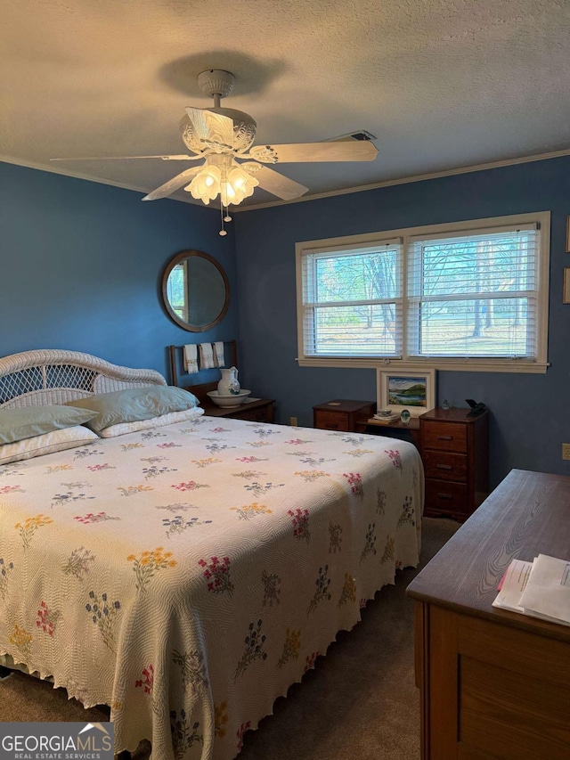 bedroom with a textured ceiling, dark colored carpet, a ceiling fan, and crown molding