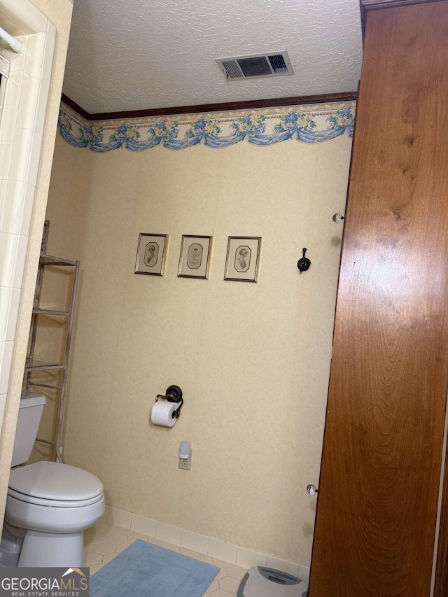 bathroom featuring toilet, tile patterned flooring, visible vents, and a textured ceiling