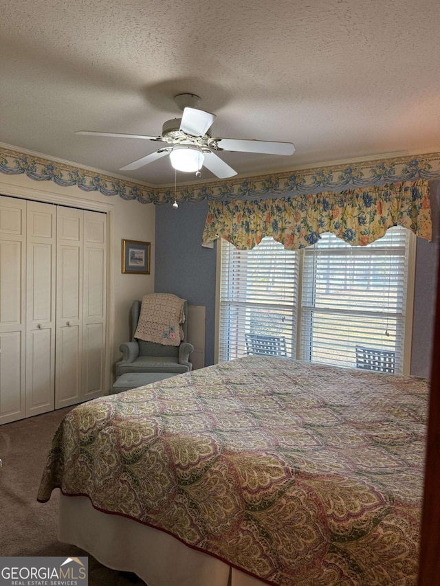 carpeted bedroom with a textured ceiling, ceiling fan, and a closet