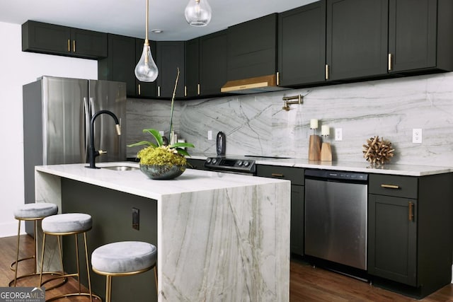 kitchen featuring dark hardwood / wood-style floors, a breakfast bar area, backsplash, a kitchen island with sink, and stainless steel appliances