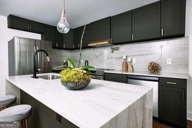 kitchen featuring hanging light fixtures, a kitchen breakfast bar, stainless steel appliances, tasteful backsplash, and an island with sink