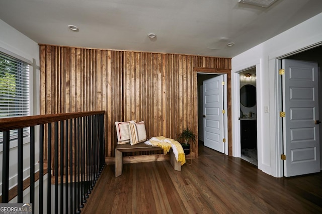 living area featuring dark wood-type flooring and wooden walls