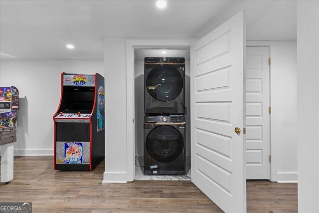 laundry area featuring stacked washer / drying machine and hardwood / wood-style floors