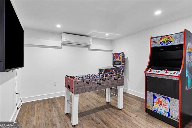 recreation room with wood-type flooring and an AC wall unit